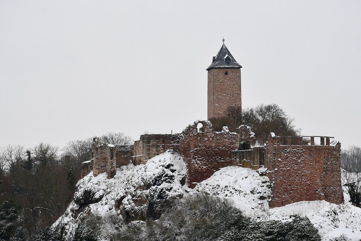 Die Ruine der Oberburg Giebichenstein auf einem verschneiten Felsen, darüber ein Turm mit dunklem Spitzdach