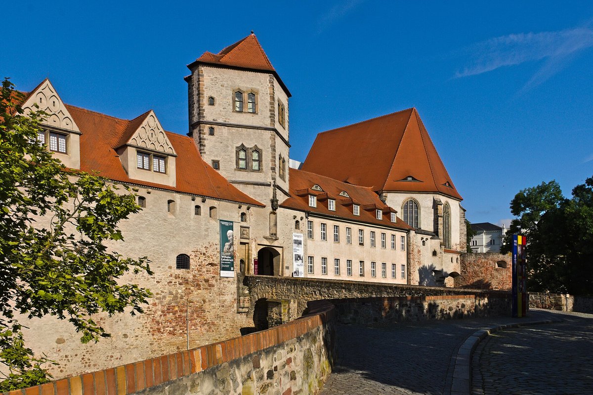 Der Turm der Moritzburg in Halle mit rotem Pyramidendach, rechts eine Kirche mit steilem Dach